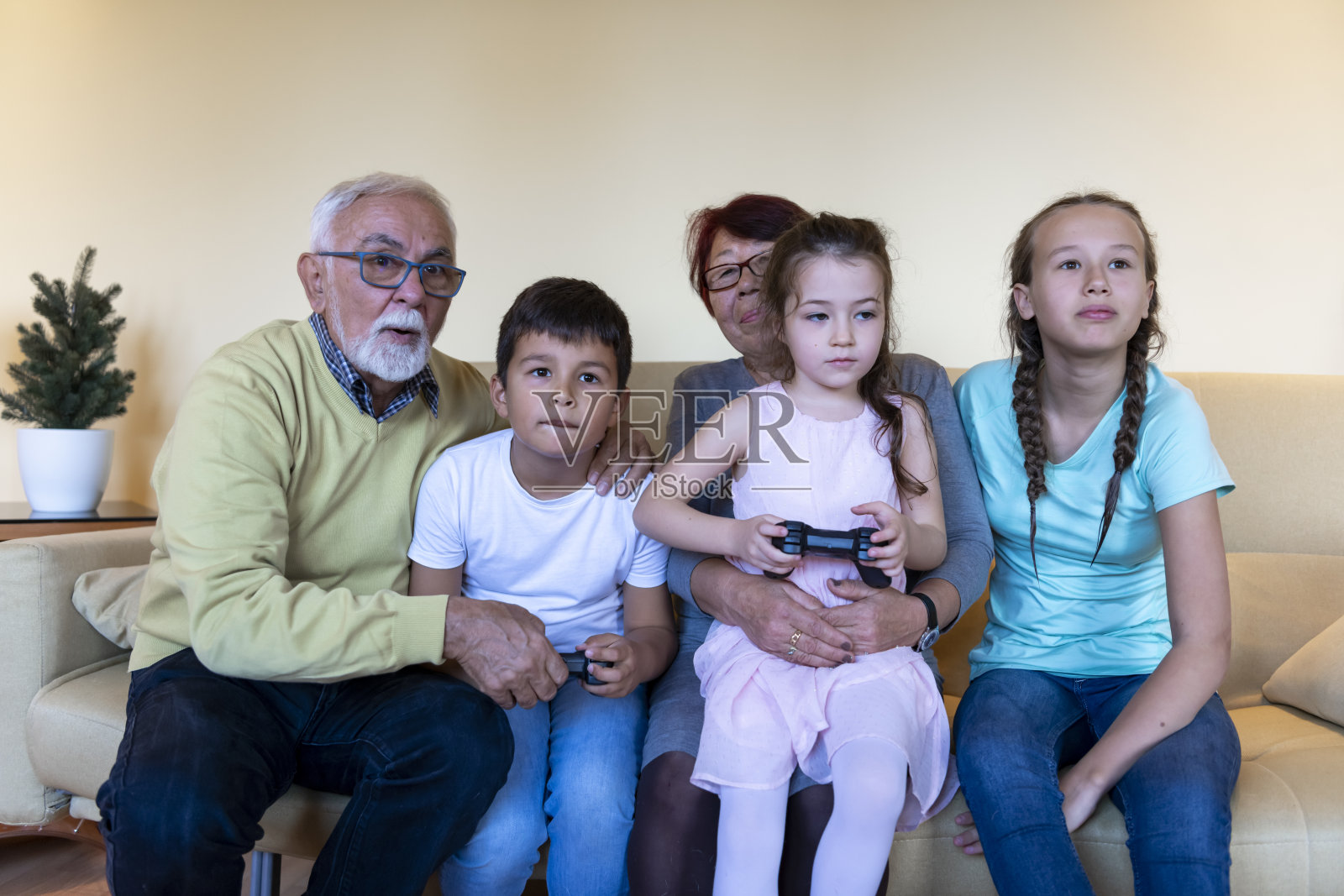 一个快乐的小女孩和她的弟弟在客厅里玩电脑游戏。照片摄影图片