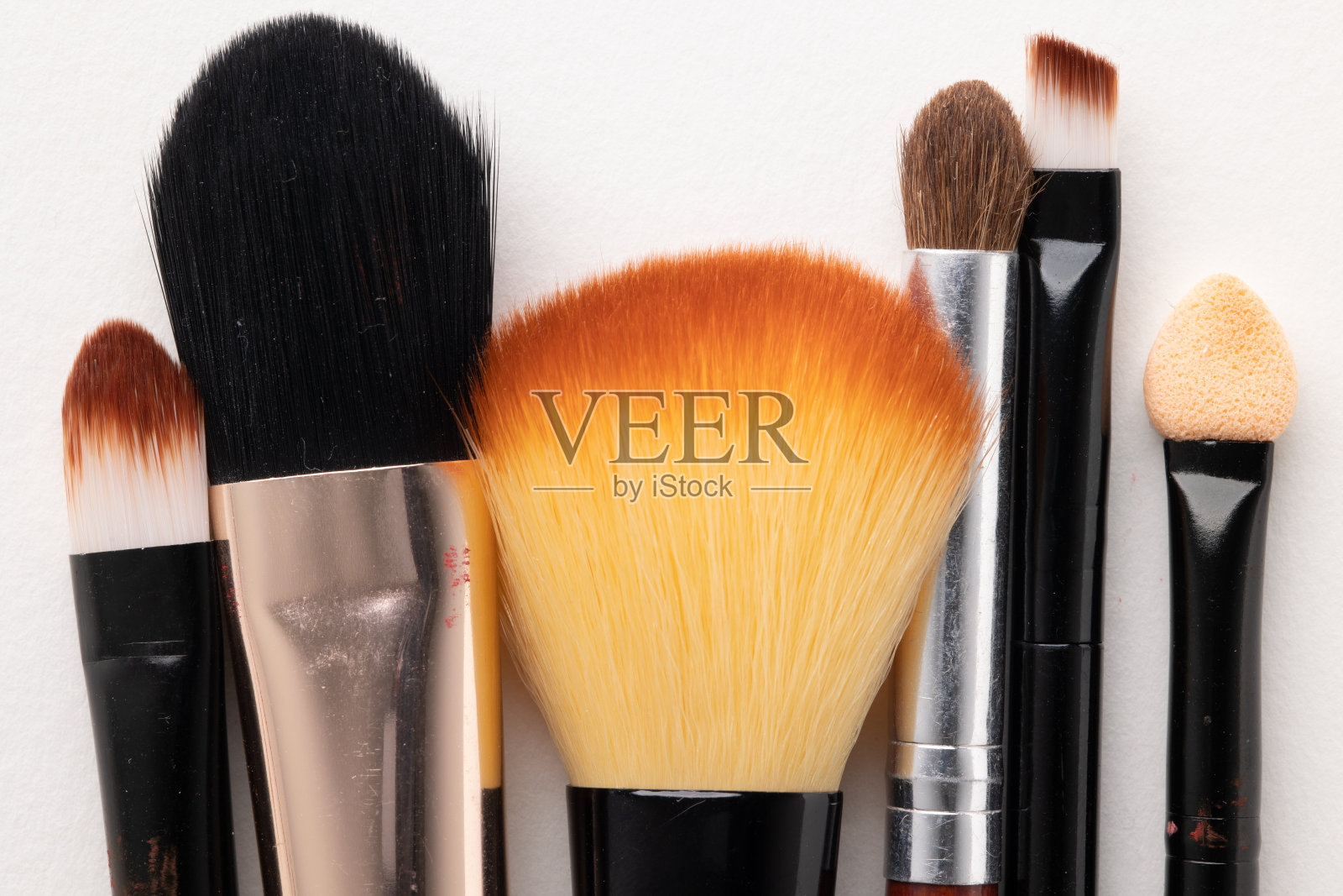 俯视图化妆品化妆为女性在白色的桌子背景与不同的刷类型。照片摄影图片