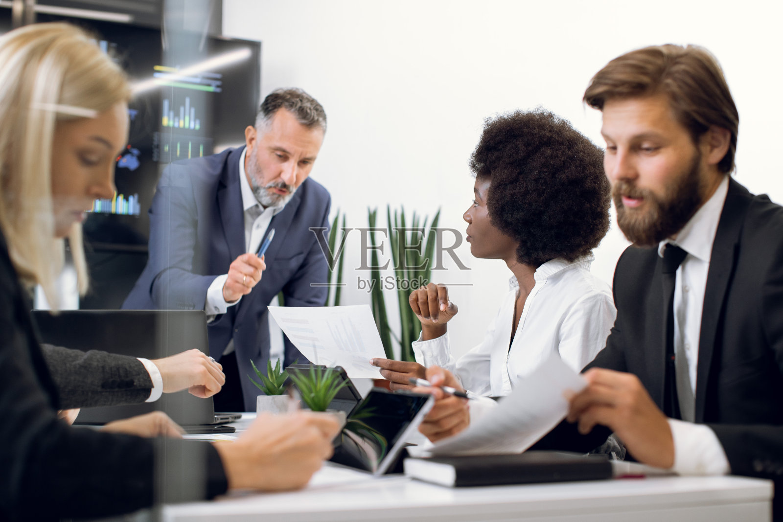 自信的中年男性老板在办公室简报中与多样化的专注的商业团队交谈和合作，讨论商业想法，并向非洲女性展示史密斯照片摄影图片