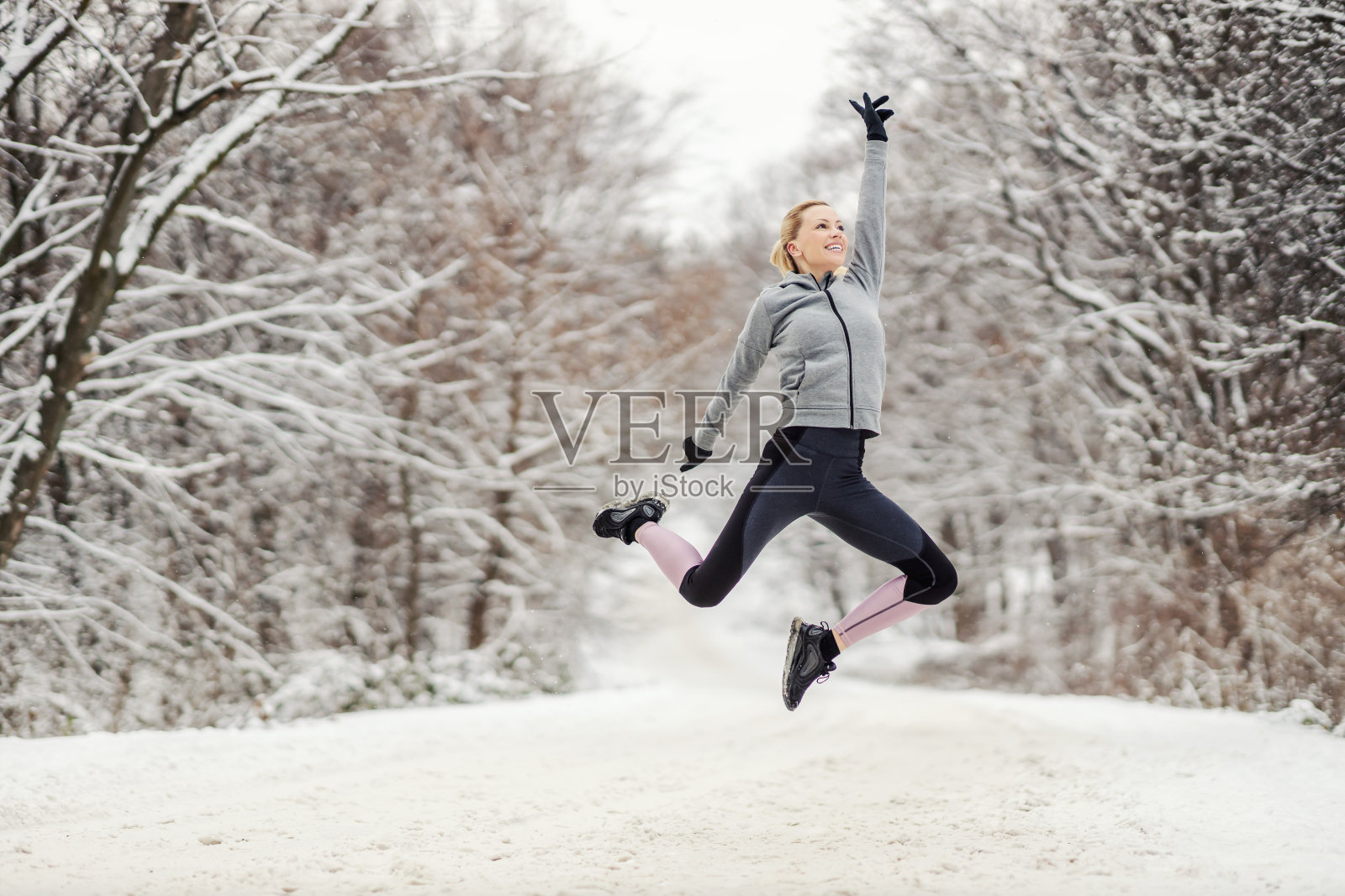 快乐的女运动员在雪天的大自然中跳得很高。快乐，自由，冬天健身照片摄影图片
