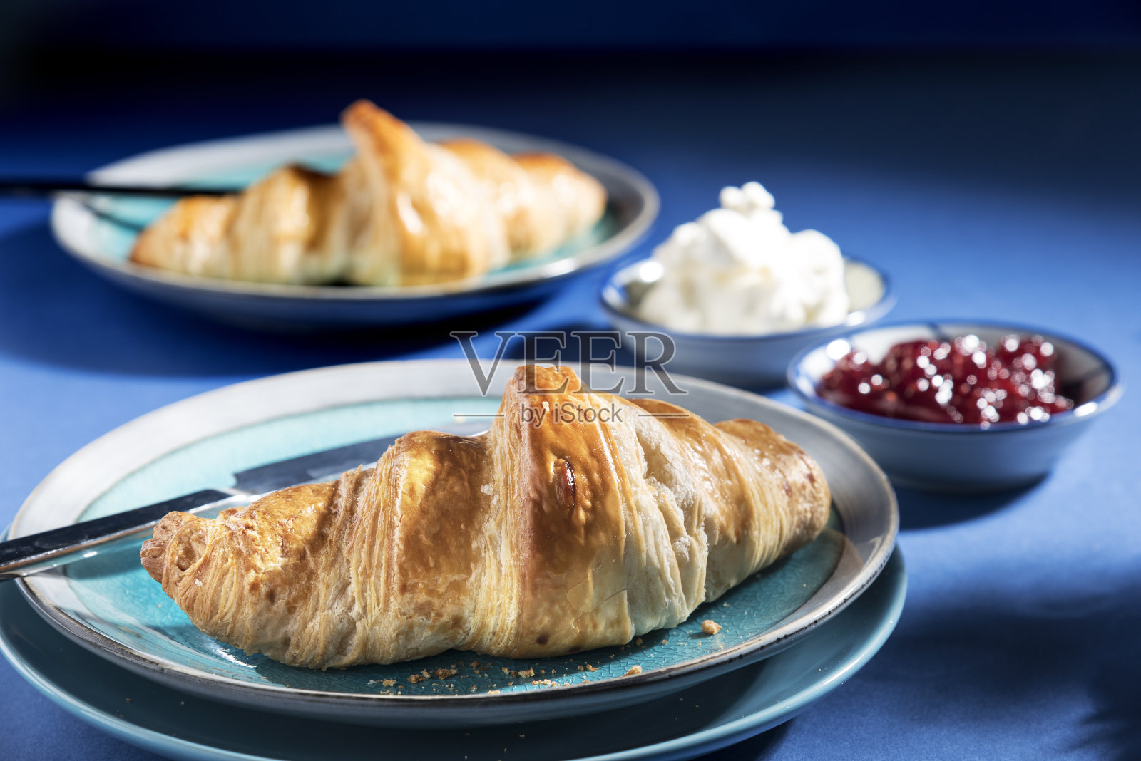 牛角面包与草莓酱，奶油和更多的牛角面包在背景，建议早餐-库存照片照片摄影图片