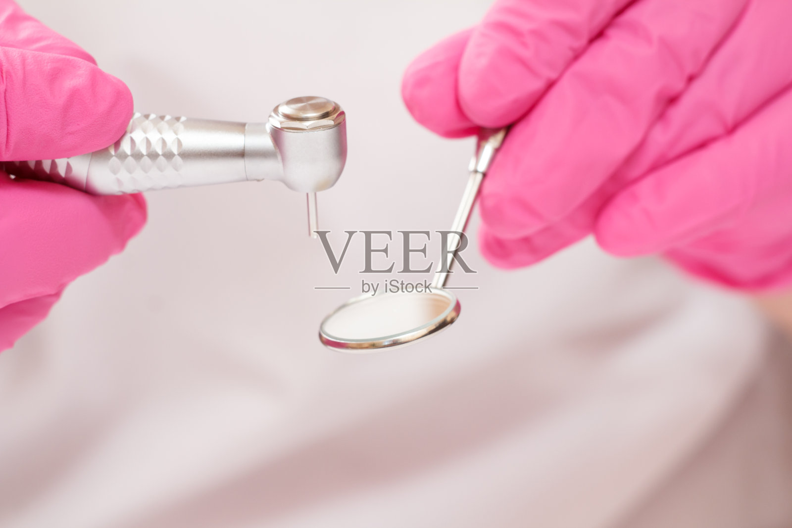 牙医的双手戴上防护手套，戴上牙科电话和口镜。照片摄影图片