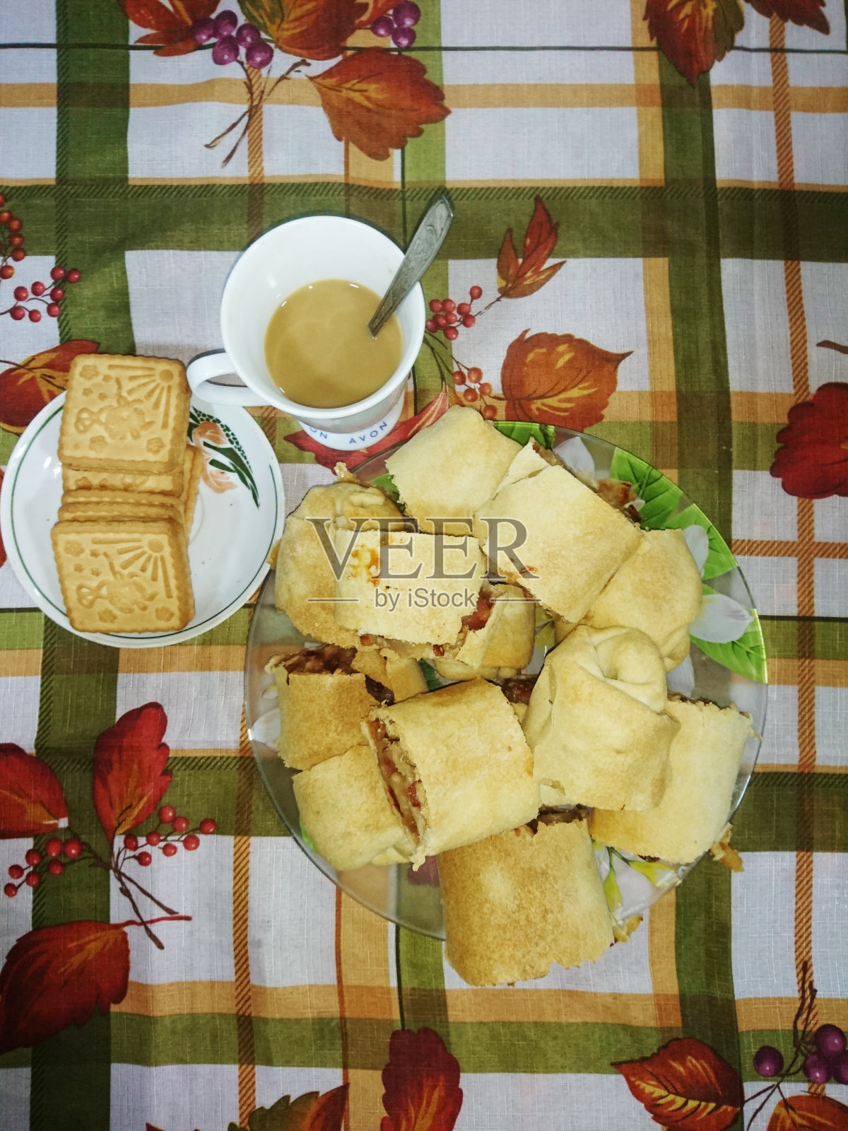 咖啡和牛奶。彩色桌布上放着饼干和自制蛋糕。照片摄影图片