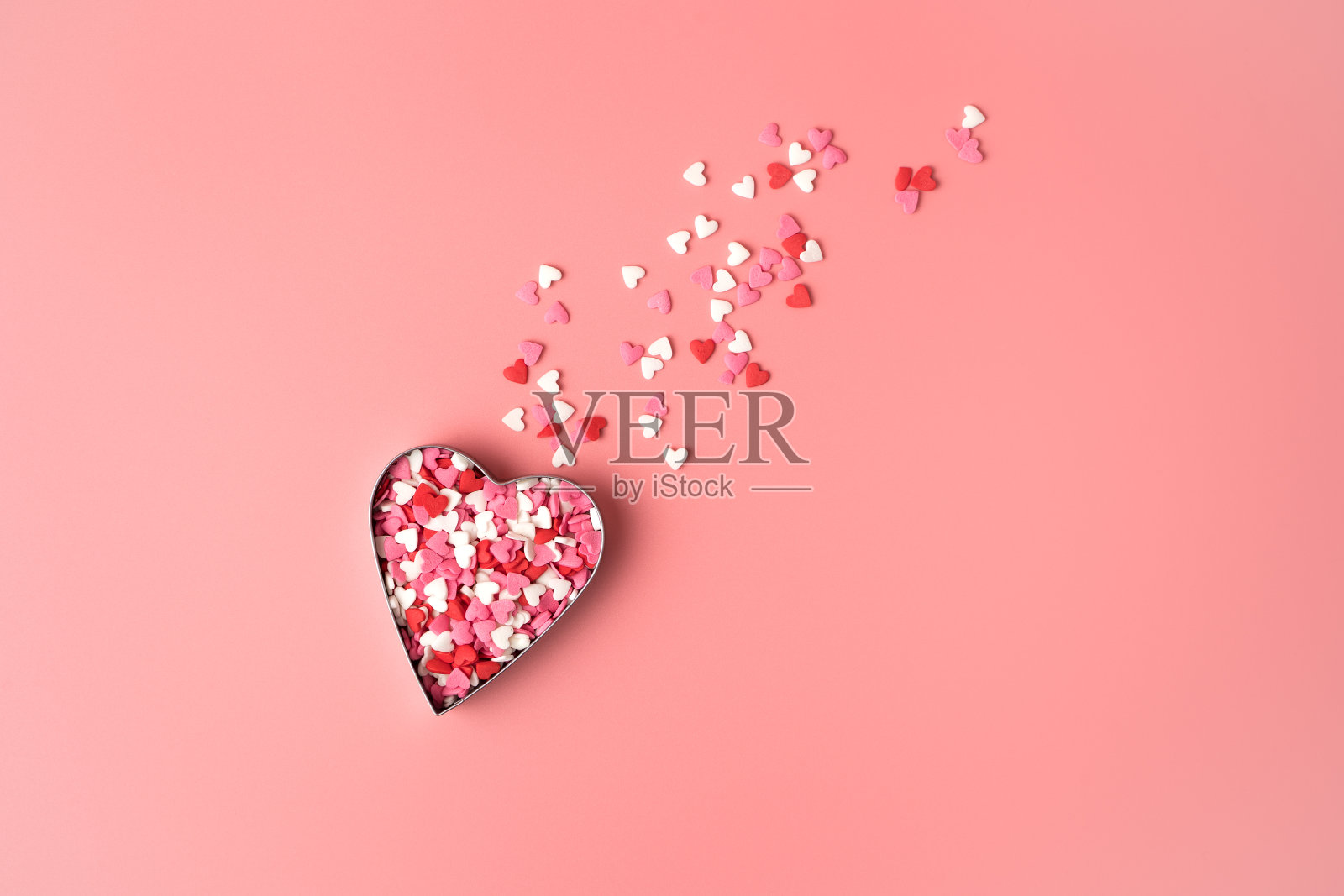 粉红色的背景上是一颗正在飞行的彗星形状的心脏照片摄影图片