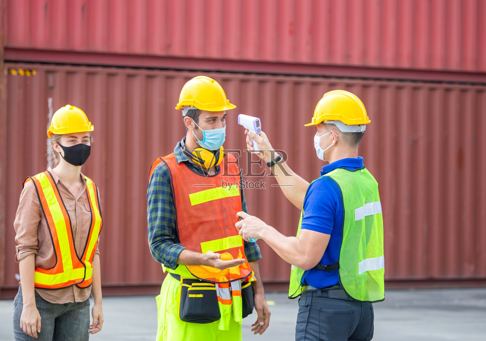 工厂工人在货物集装箱用数字温度计检查发烧并预防冠状病毒(COVID-19) -医疗概念照片摄影图片