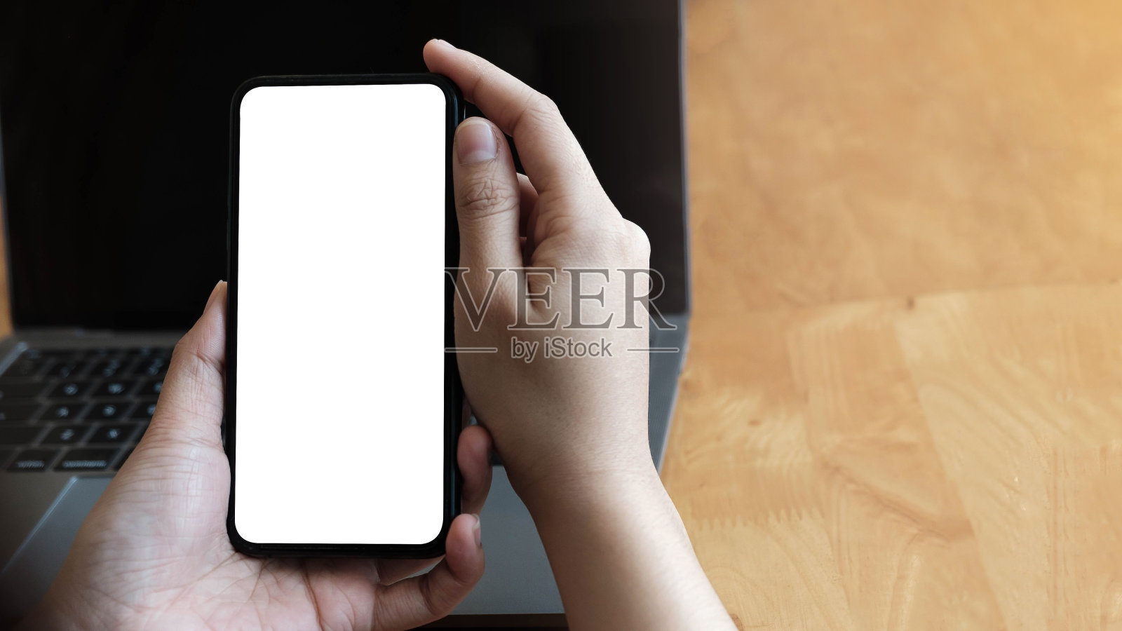 男人在白色的办公桌上用智能手机，桌子上有很多东西。黑屏手机图形显示蒙太奇。照片摄影图片