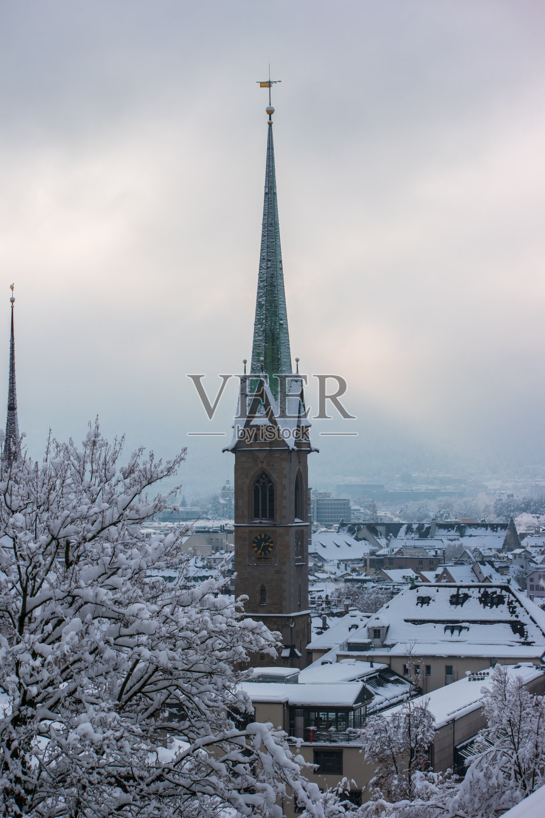 冬天阴天的时候，雪覆盖了苏黎世老城的教堂钟楼照片摄影图片