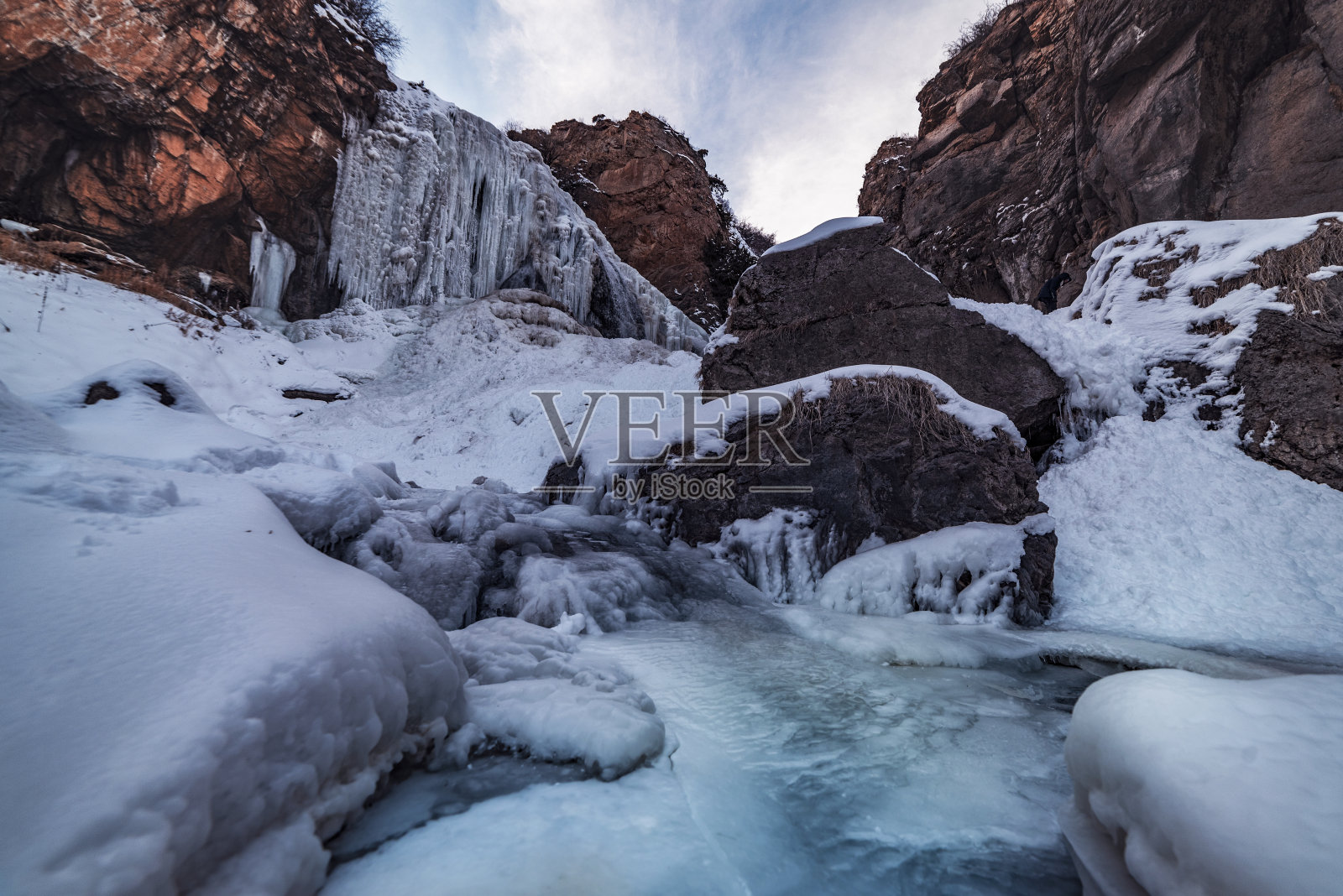 美丽的冬天的风景。冰冻的瀑布和河流，白雪覆盖的山脉。照片摄影图片
