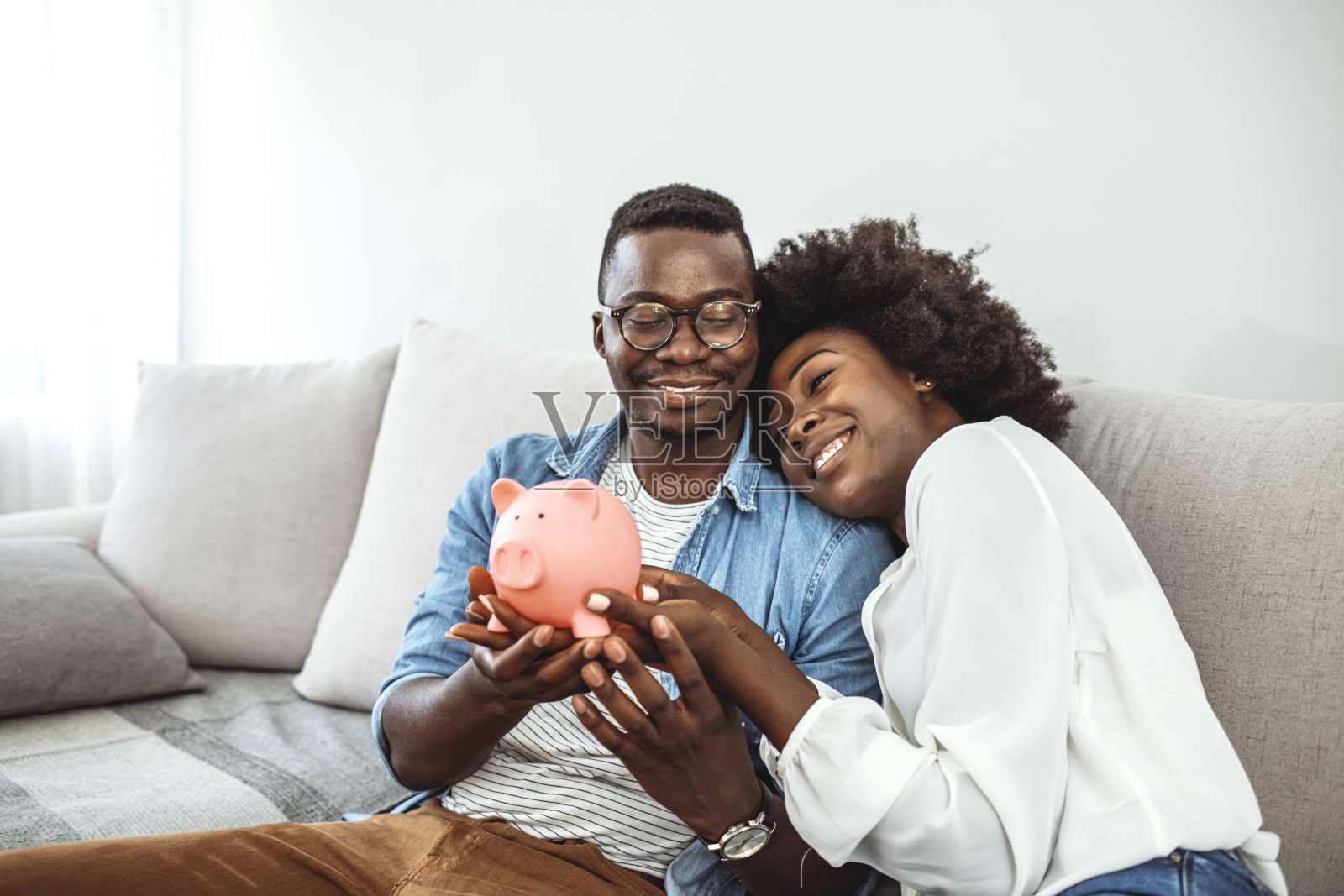 一对幸福的夫妇在存钱罐里存钱。照片摄影图片