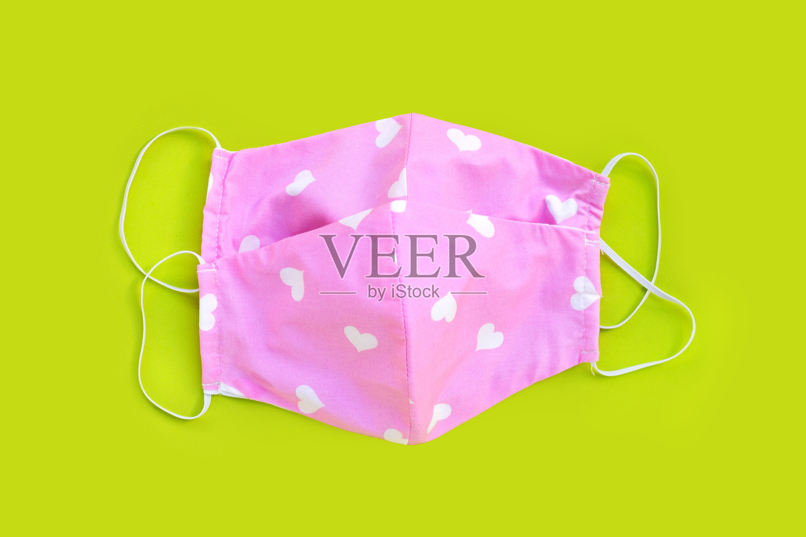 手工制作的粉色和心形布面具在绿色背景上。照片摄影图片