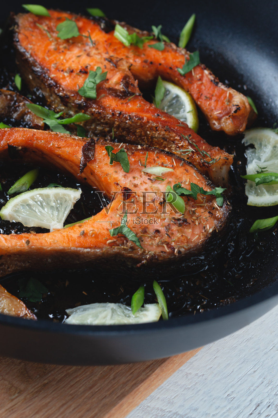 多汁的烤鲑鱼排与柠檬，香料和酸橙在轻木桌平底锅。美味的三文鱼片照片摄影图片