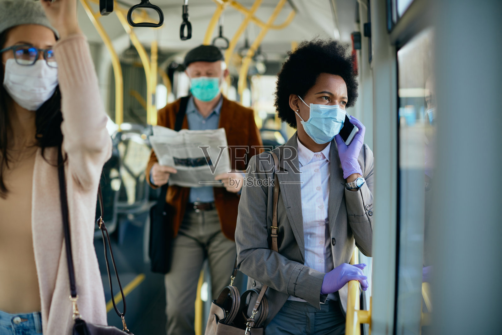 戴着面具的黑人女商人在公共交通工具上打电话。照片摄影图片