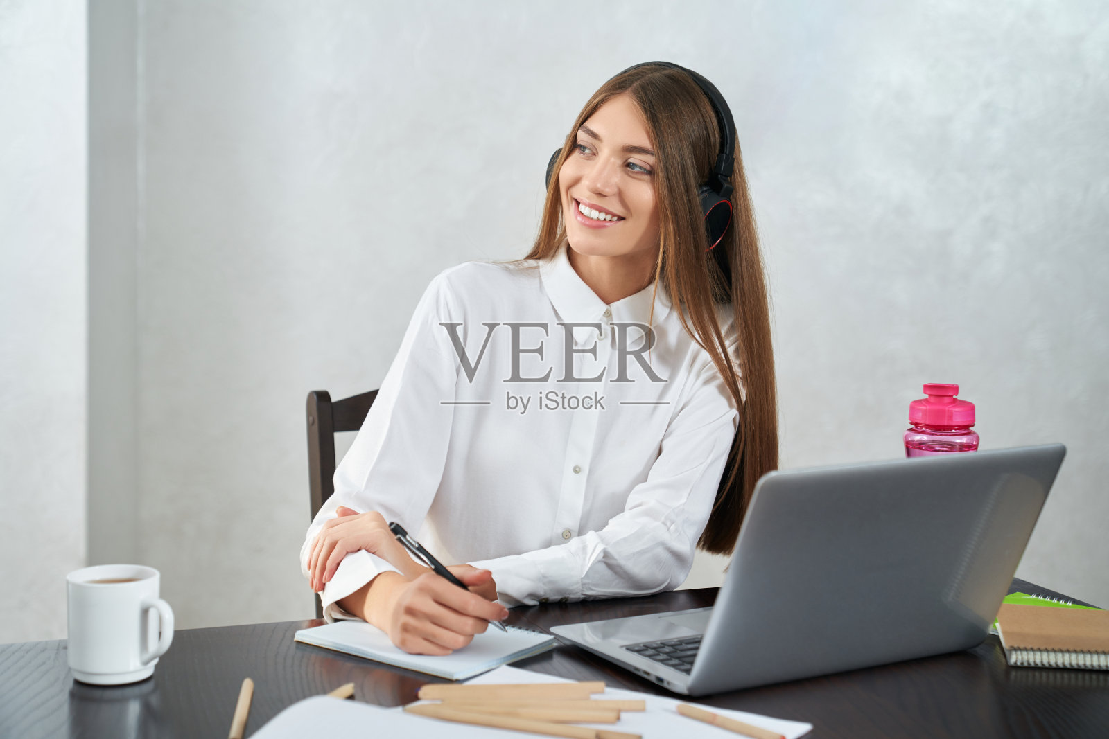 戴着耳机在笔记本电脑上学习的积极女性照片摄影图片