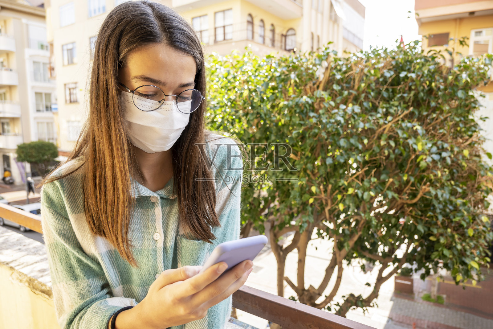 一个十几岁的女孩用手机戴着防护面具的肖像照片摄影图片