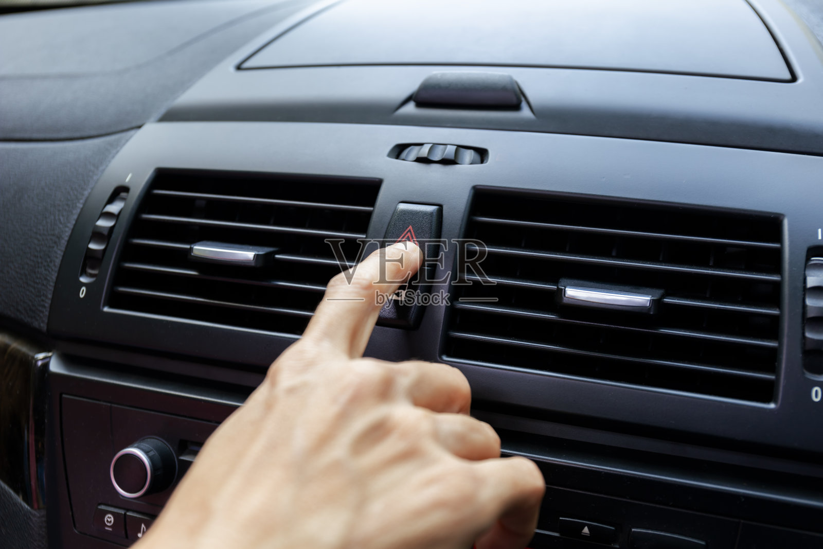 用手按住车上的应急灯，手指按下按钮。用于打开车内合同应急灯。按下紧急按钮可打开汽车外的紧急信号灯警告标志照片摄影图片