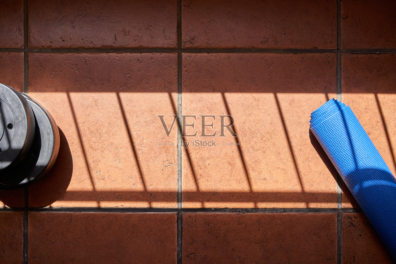 运动背景，蓝色瑜伽垫和砝码躺在地板上准备捡起来照片摄影图片