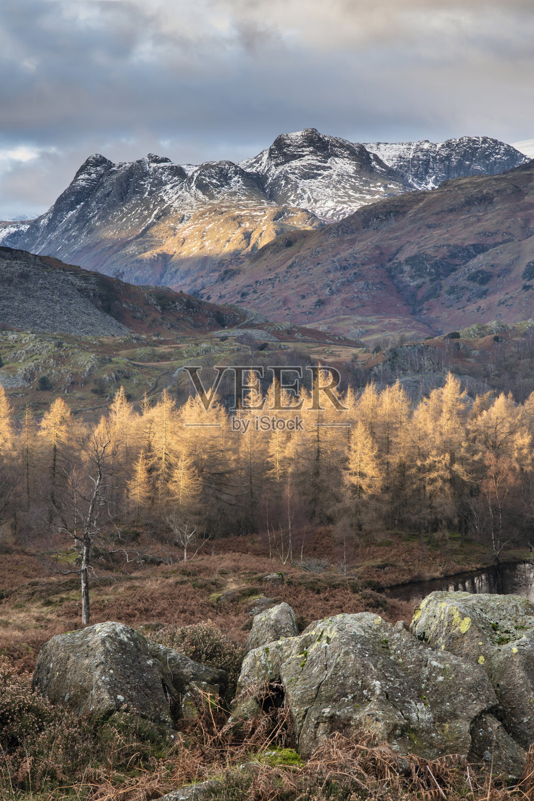 雄伟的冬季景观图像从霍姆瀑布在湖区向雪山山脉在辉煌的傍晚光与秋天的颜色树的距离照片摄影图片