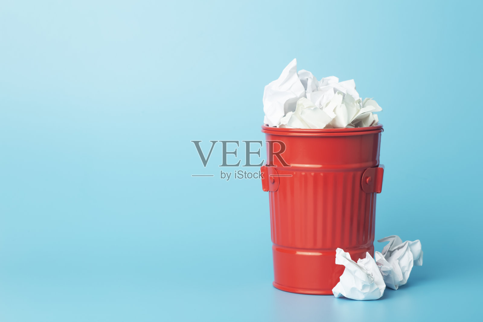 蓝色背景下垃圾桶里的废纸和废物。废纸分类回收理念照片摄影图片