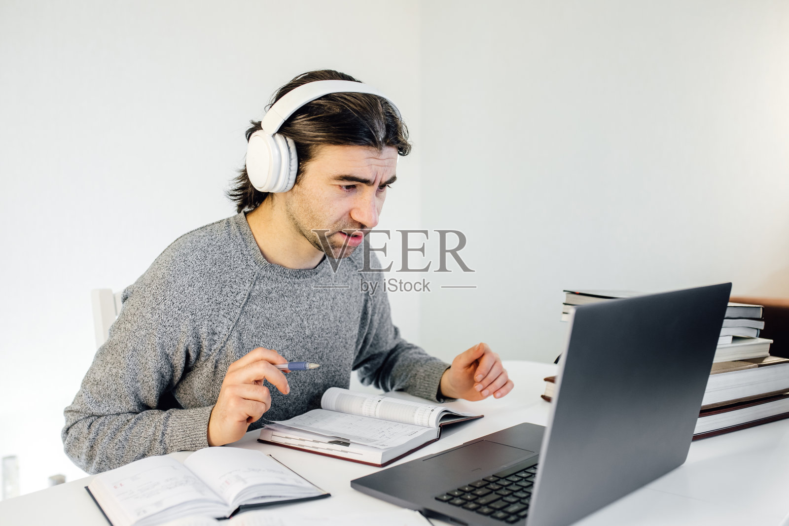 盖伊学生戴着耳机使用笔记本电脑进行远程教育，享受视频会议，观看网络研讨会，听音频课程，写笔记，与老师一起学习，上课照片摄影图片