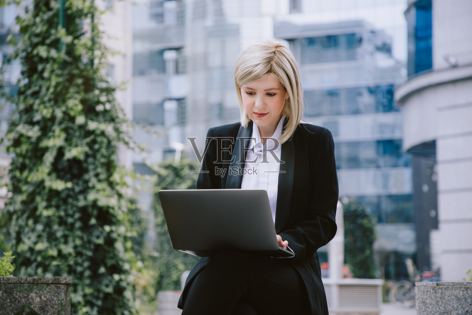 一名年轻女子在商业中心附近的户外用笔记本电脑工作。照片摄影图片