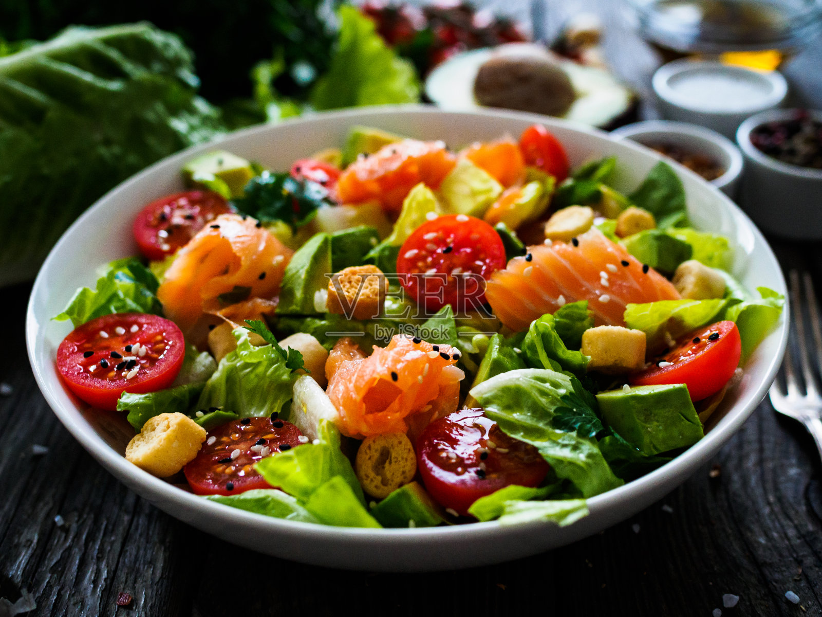 木桌上放着熏鲑鱼、鳄梨和蔬菜照片摄影图片