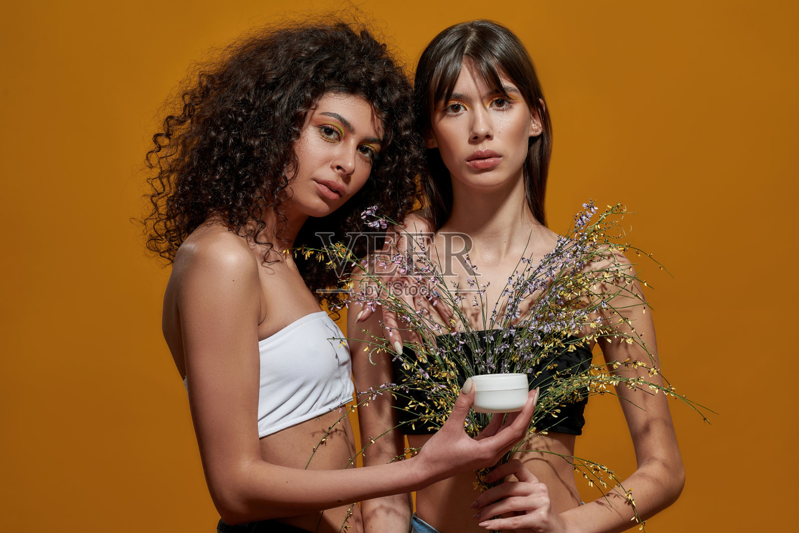 女人展示化妆品容器前的花组成照片摄影图片