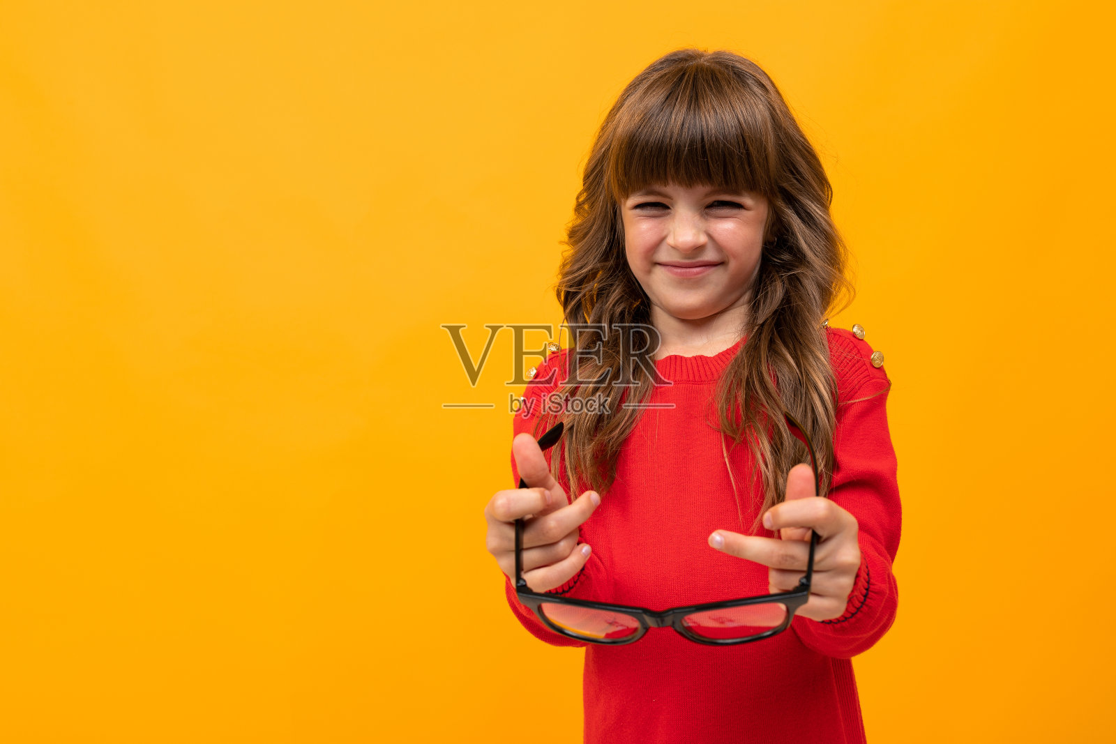 美丽的小女孩穿着衣服玩眼镜孤立在黄色和橙色的背景照片摄影图片