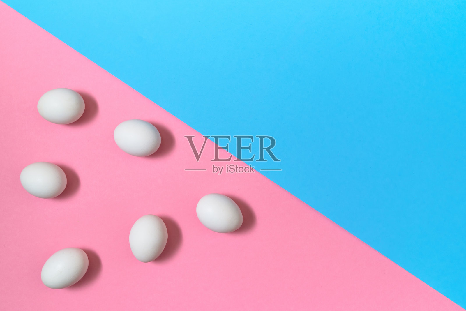 白色鸡蛋上的蓝色和粉色粉彩背景，复制空间。煮鸡蛋在纸上的背景有两种色调。健康食品的概念。复活节彩蛋。平躺，俯视图照片摄影图片