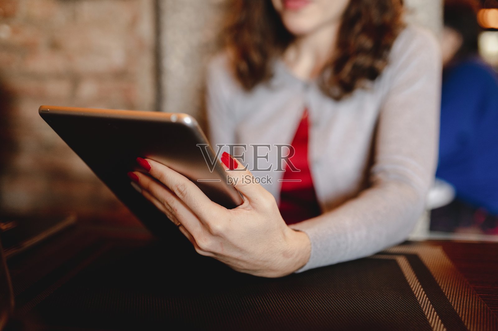 不认识的女人手拿着写字板坐在餐厅的桌子上。照片摄影图片