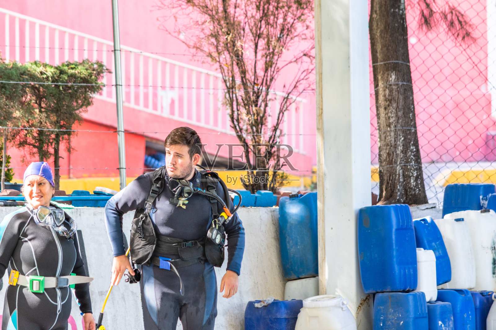 两名年龄不同的潜水员站在泳池外聚精会神照片摄影图片