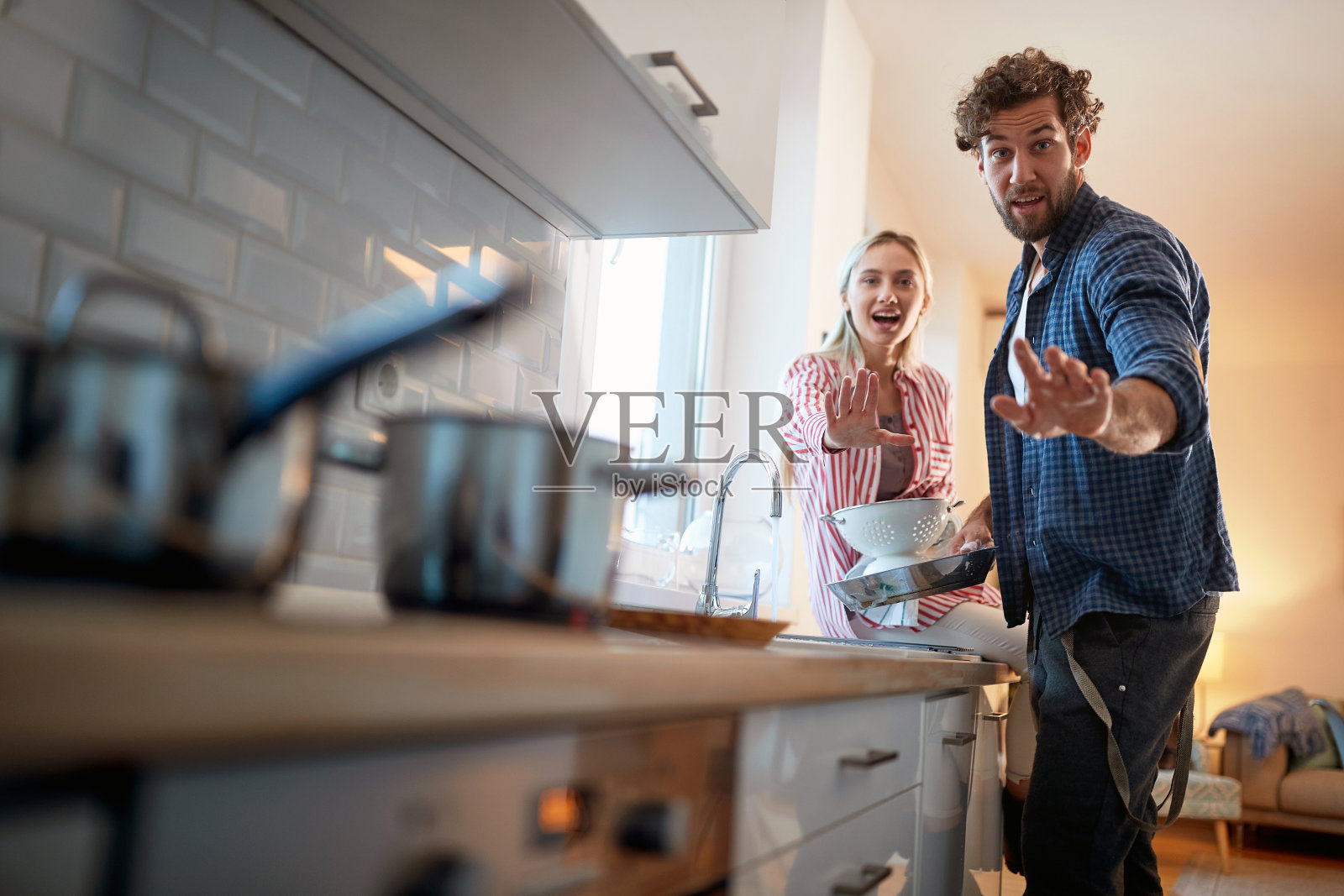 一对年轻夫妇在做家务时摆姿势拍照。厨房，家务，家庭，人际关系照片摄影图片