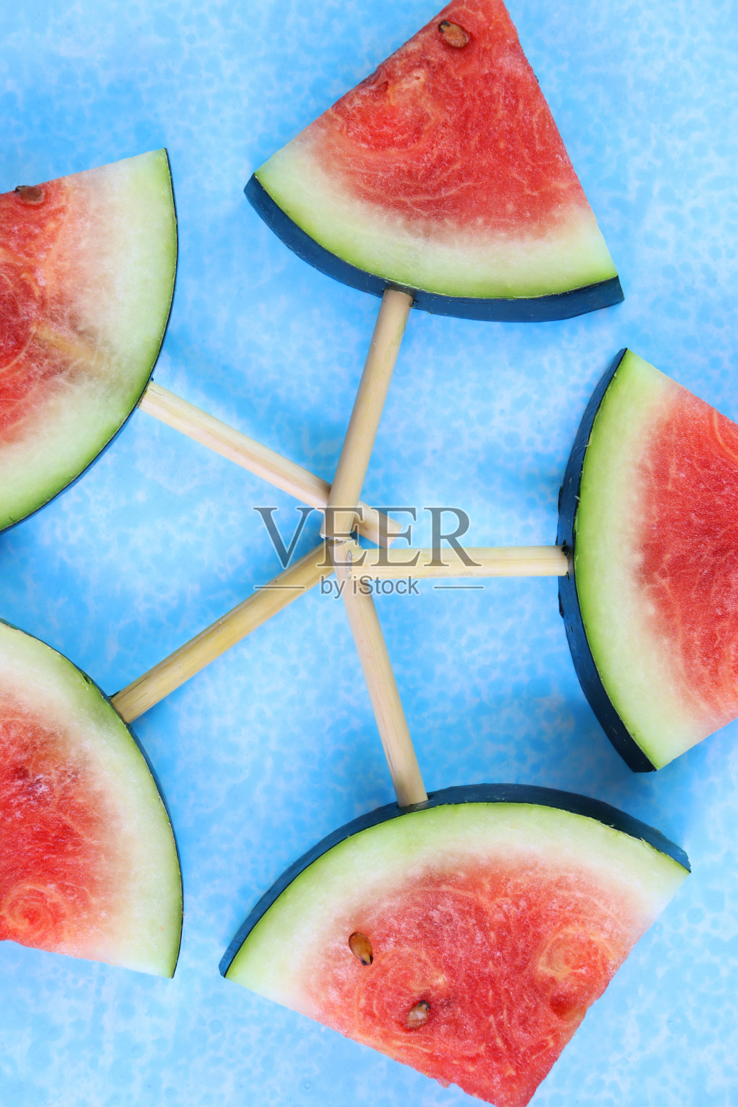 西瓜片/块的特写图像冰棒棍棒上的五角形，切成三角形，蓝色的背景，高架视图照片摄影图片