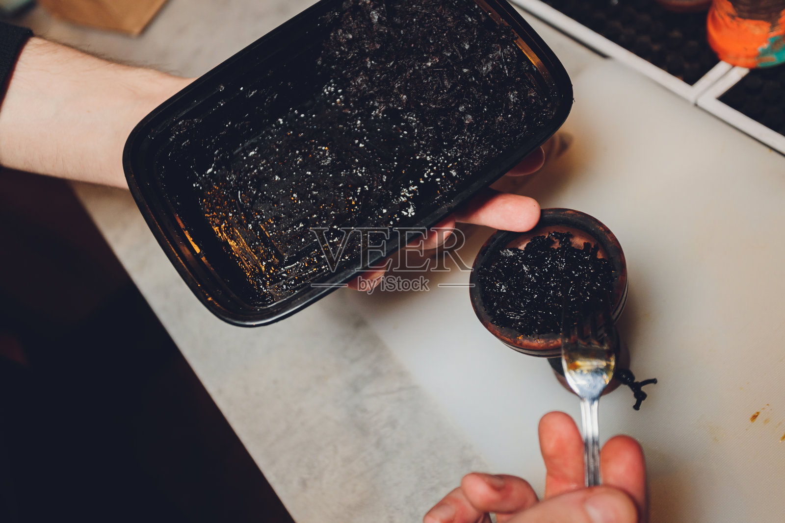 一个人吸烟。这个人正在准备水烟管。有一张桌子。照片摄影图片