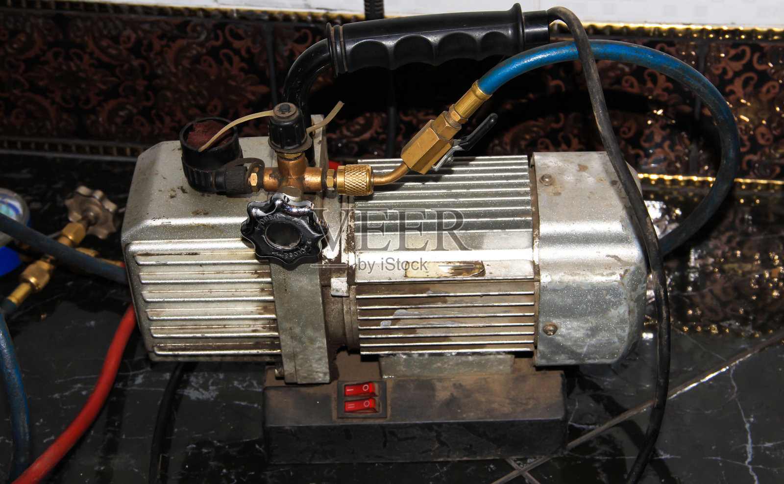 从冰箱中抽frion的机制。收集氟利昂的工作站。真空泵。照片摄影图片