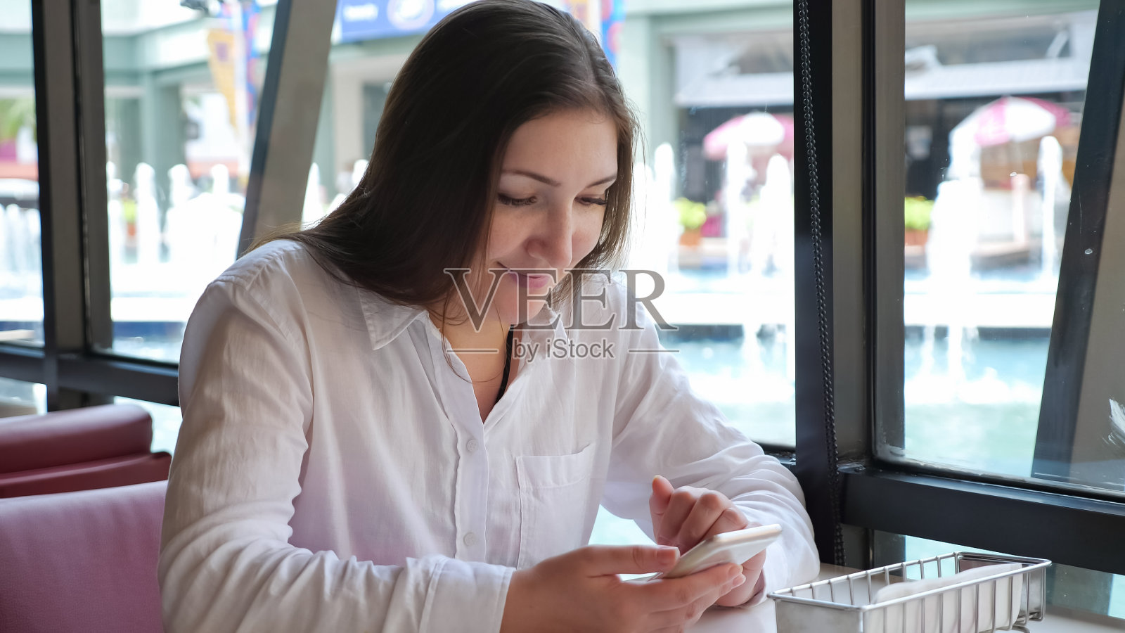 咖啡店里一个拿着手机的黑发女人照片摄影图片