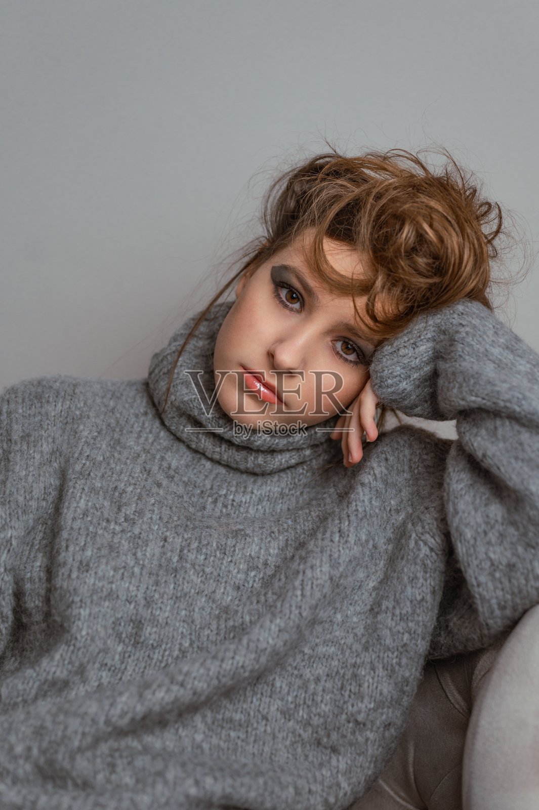 一个年轻女孩的肖像化妆和凌乱的发髻。照片摄影图片