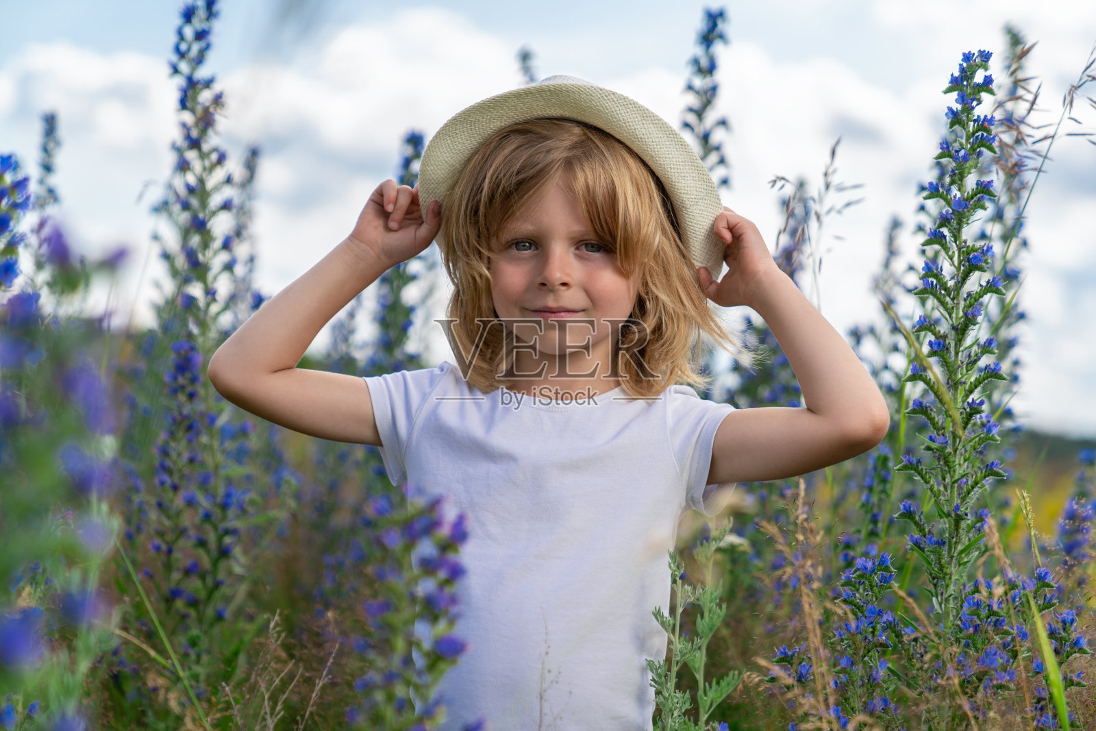 金发男孩在鲜花草地上散步照片摄影图片