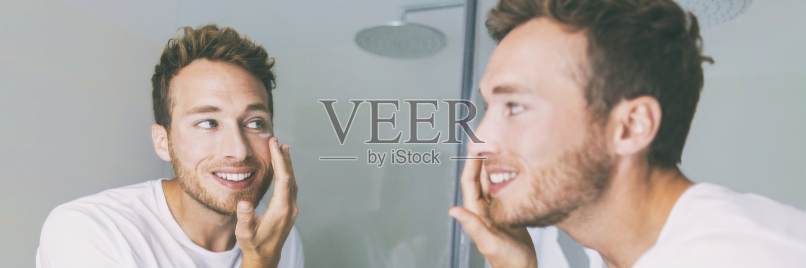 男人在浴室的镜子横幅上涂奶油。小伙子在眼部涂抹抗衰老的保湿产品进行面部护理。男性美容晨间例行在家生活方式照片摄影图片