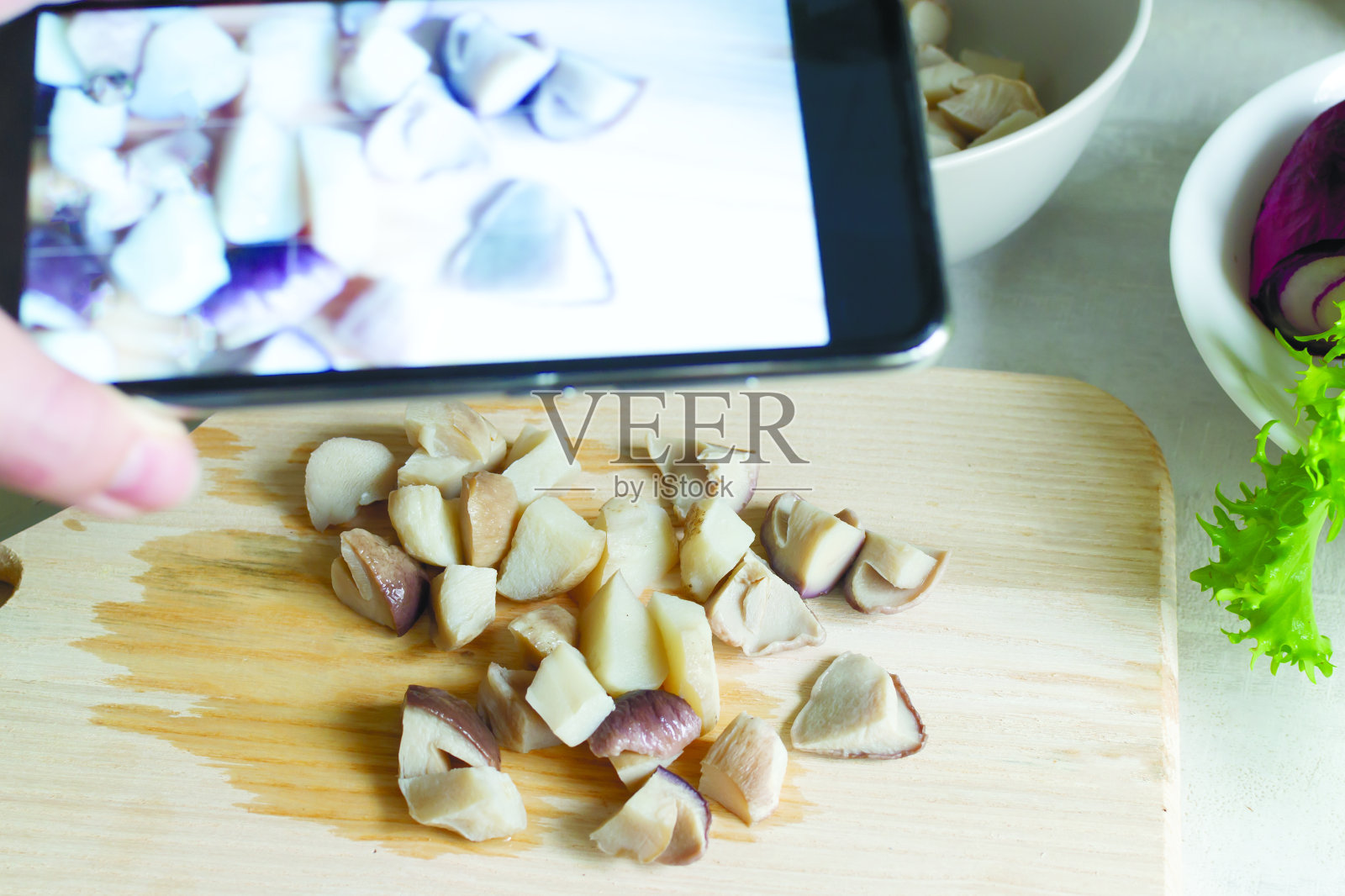 一名妇女在厨房的木板上拍摄牛肝菌。美食博客。照片摄影图片