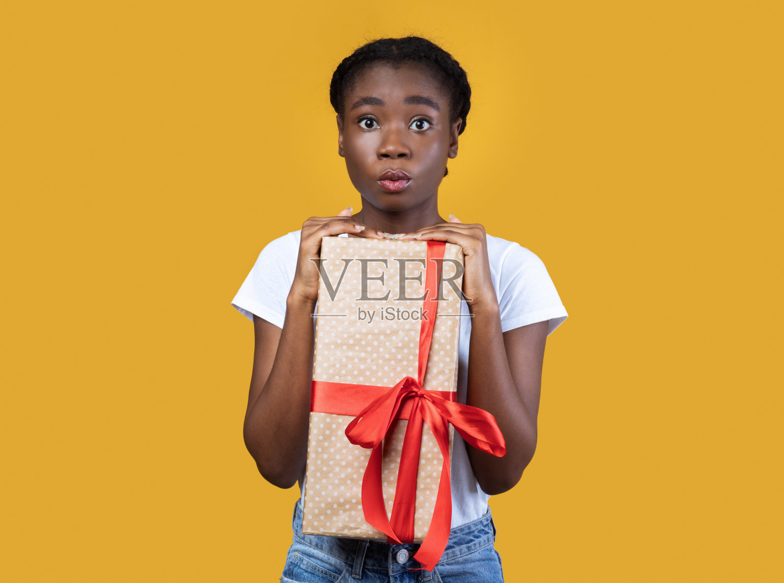 非洲妇女拿着包装的礼品盒在黄色背景下摆姿势照片摄影图片