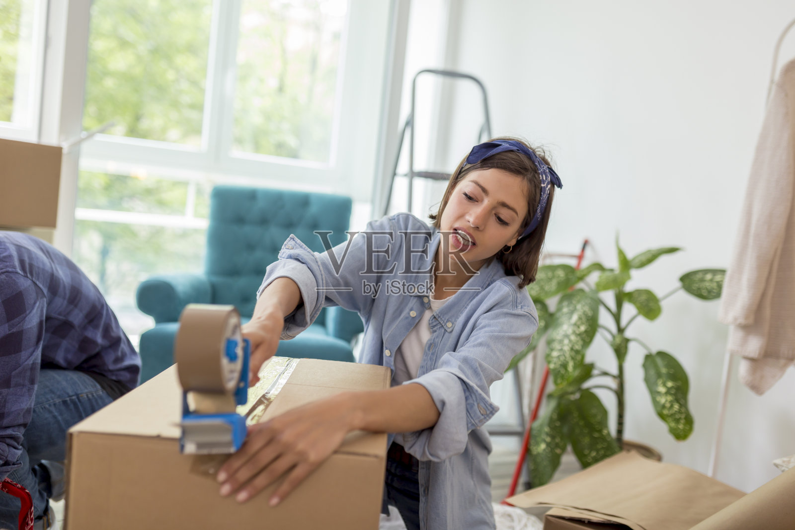 一个女人用胶带机，在搬家的时候打包箱子照片摄影图片