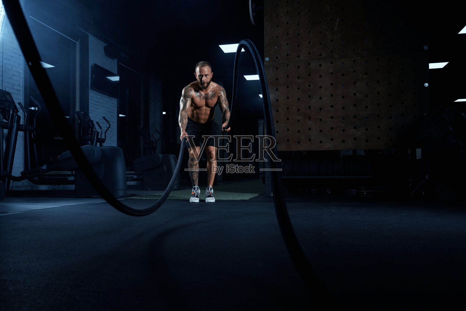 用绳子训练的肌肉发达的运动员。照片摄影图片