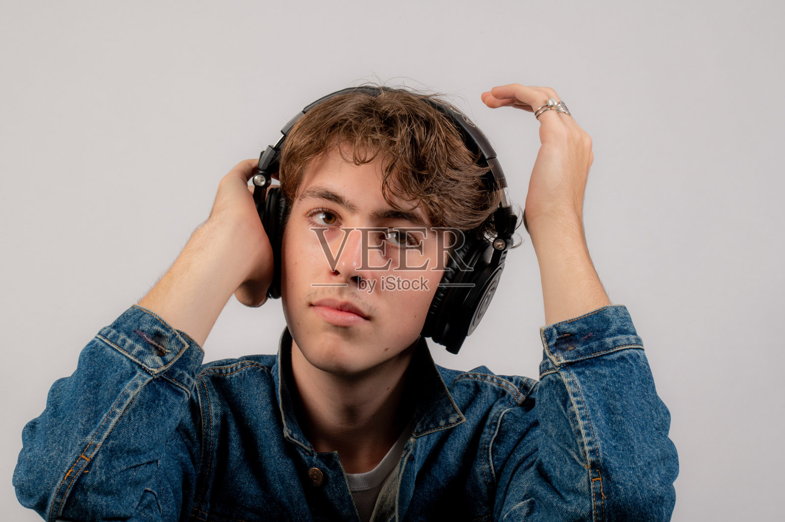 十几岁的男孩一边听音乐一边调整耳机。照片摄影图片