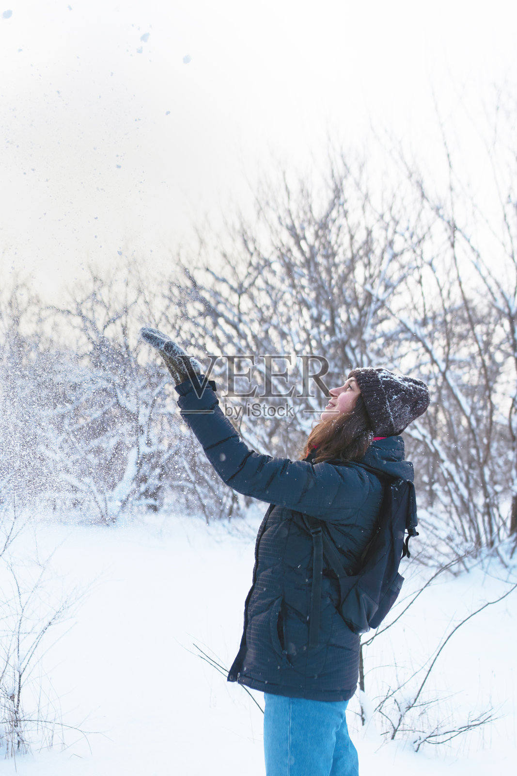 美丽的女人在白雪覆盖的森林里玩。照片摄影图片