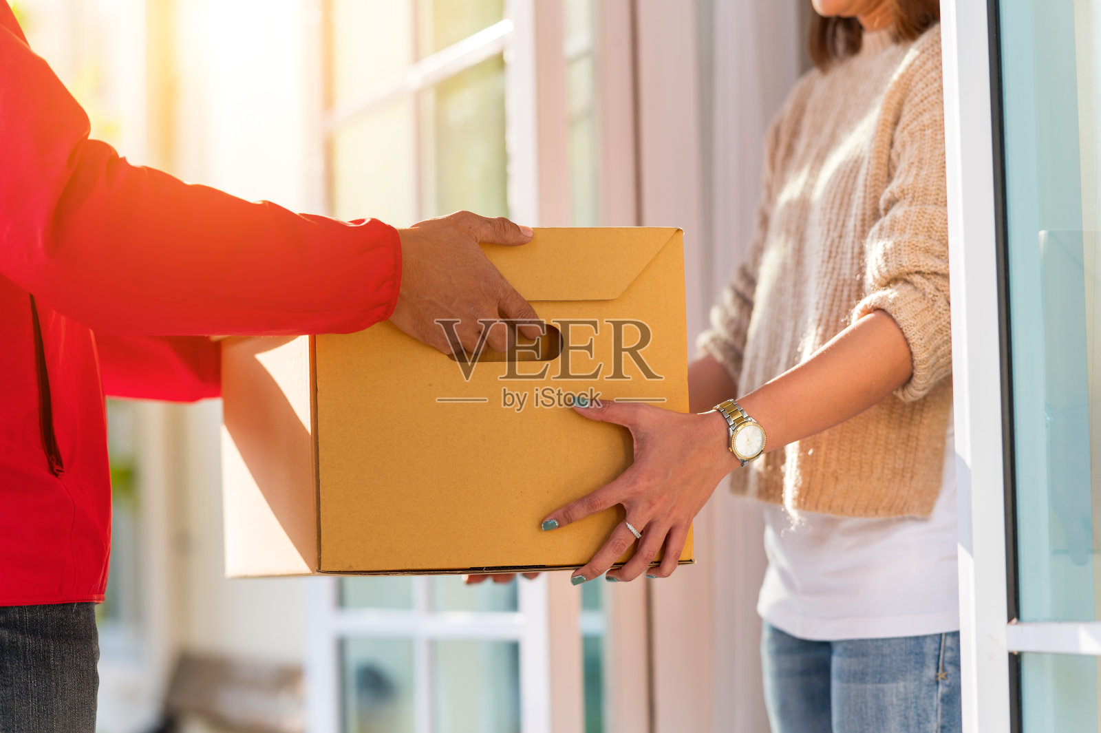 快递员在家给年轻女性送盒子，快递服务理念照片摄影图片