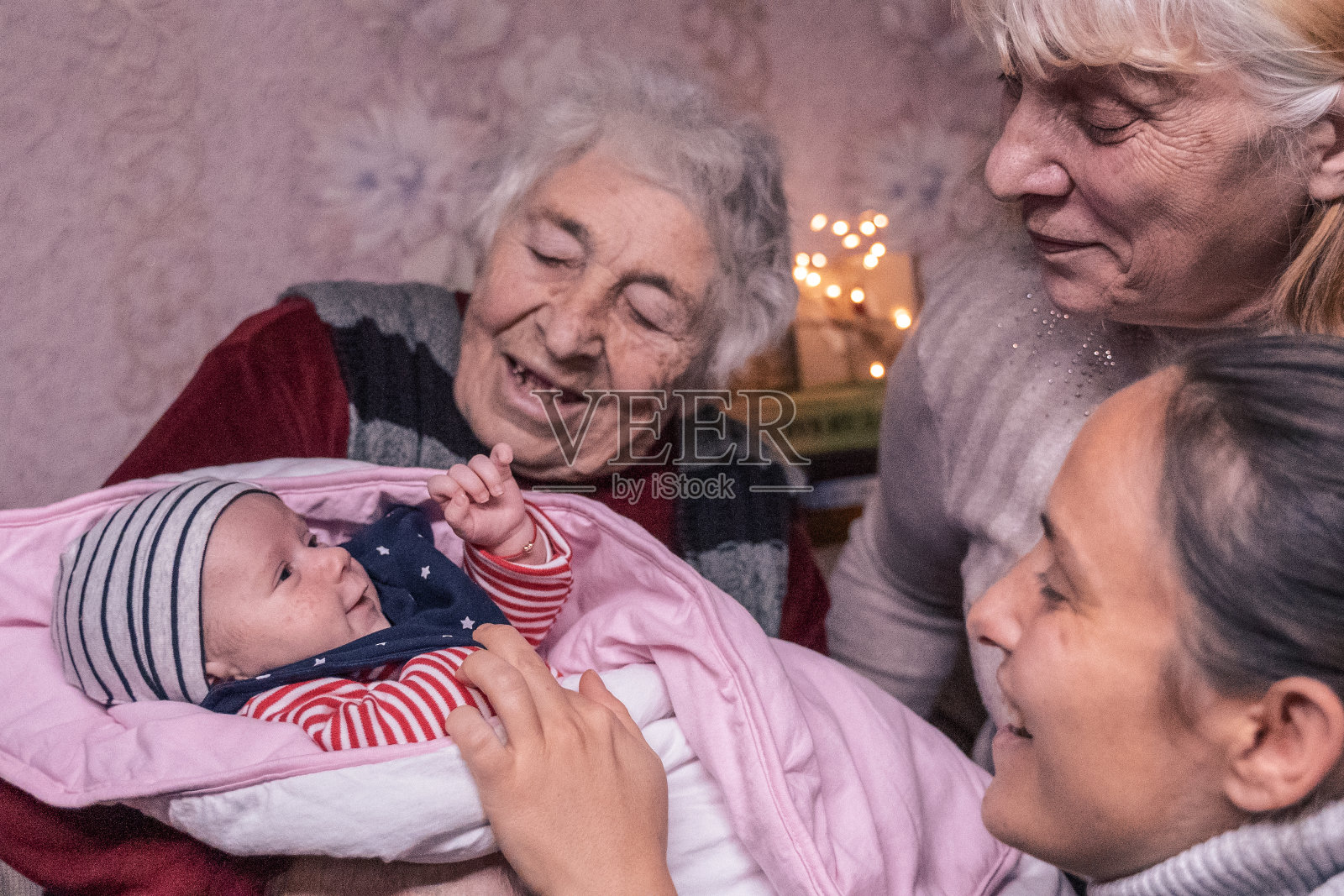 四代人一起在家里过节。曾祖母、祖母、女儿和孙女聚集在家里过圣诞节。COVID-19大流行期间的新生儿。特写肖像。照片摄影图片