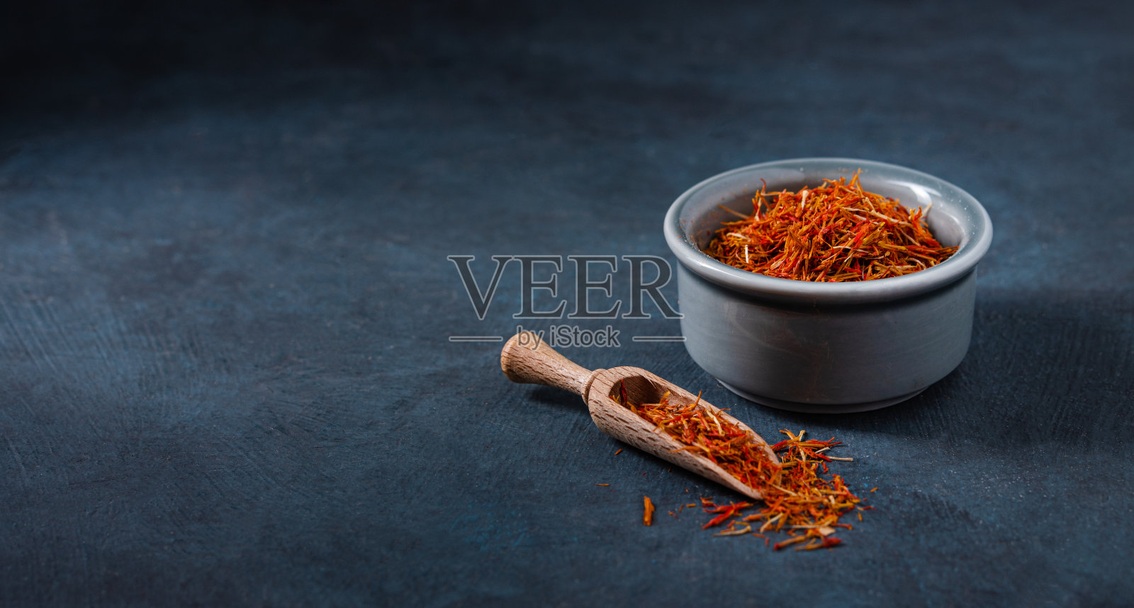 黑色桌子上的蓝色陶瓷碗里盛着东方香料和藏红花。照片摄影图片