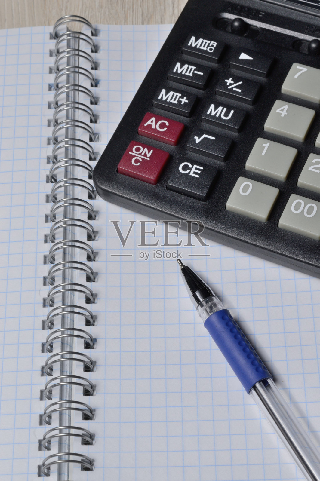方形笔记本上放着一支圆珠笔和一个微型计算器。特写镜头。照片摄影图片