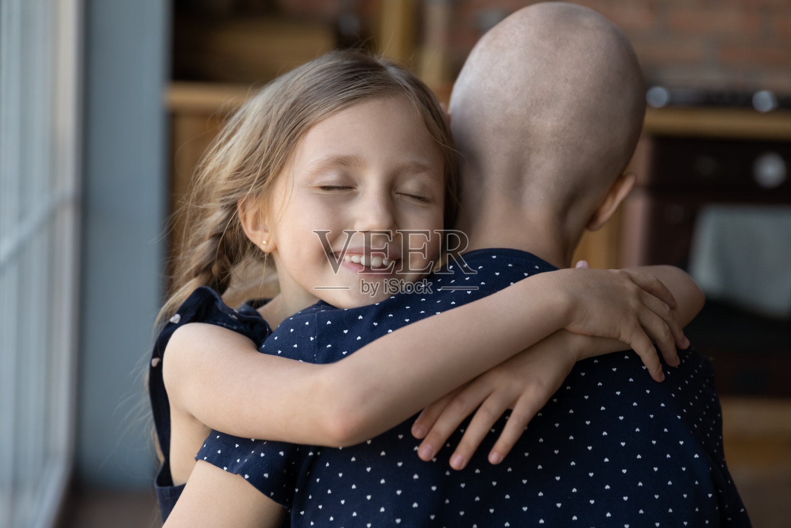 近距离微笑的小女儿拥抱生病的无毛母亲照片摄影图片