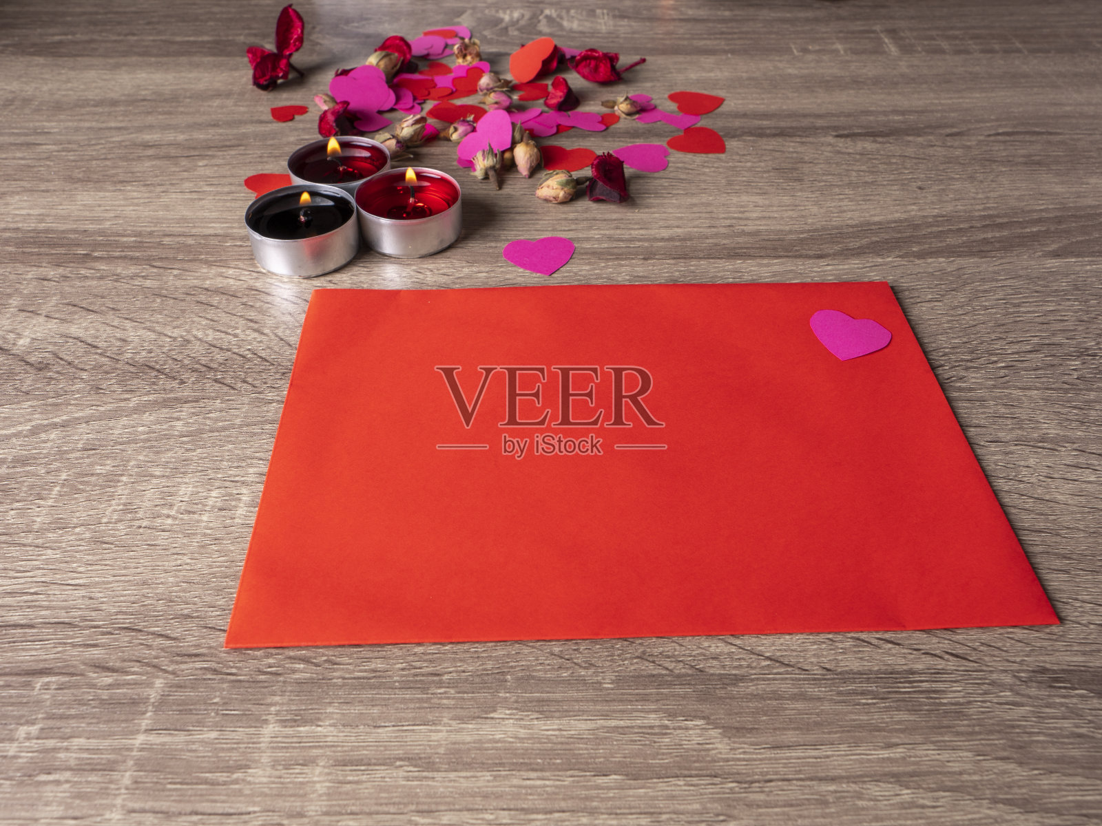 红包旁边的蜡烛上插着红玫瑰照片摄影图片